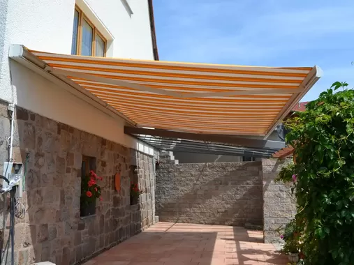 Ausgefahrene Terrassenmarkise an einem Einfamilienhaus sorgt für angenehmen Sonnenschutz auf der Terrasse