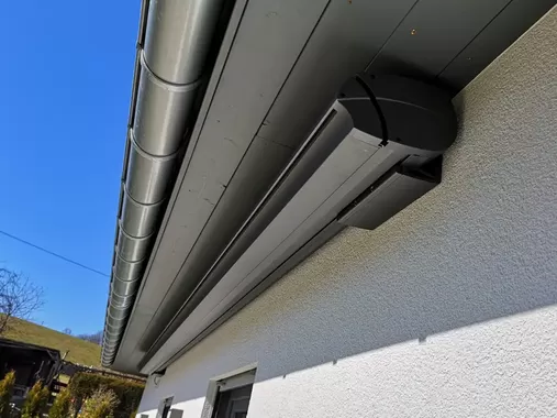 Detailaufnahme einer Kassettenmarkise an einer Hausfassade mit ausgefahrenem Sonnenschutzsystem