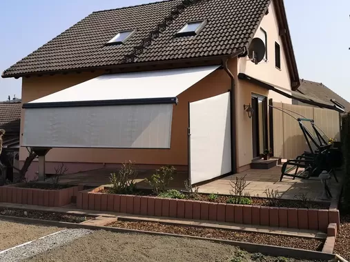 Große Gelenkarmmarkise an einem Einfamilienhaus sorgt für effektiven Sonnenschutz auf Terrasse und Balkon
