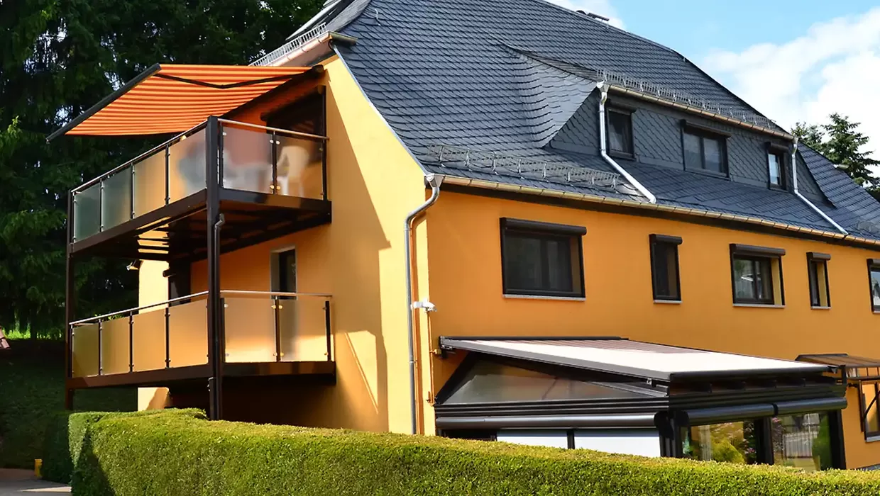 Mehrere Balkonmarkisen an einem Wohnhaus sorgen für Schatten und schützen Balkone vor intensiver Sonneneinstrahlung