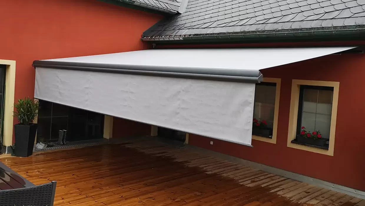 Ausgefahrene Terrassenmarkise an einem Einfamilienhaus spendet Schatten und schützt den Sitzbereich vor Sonne